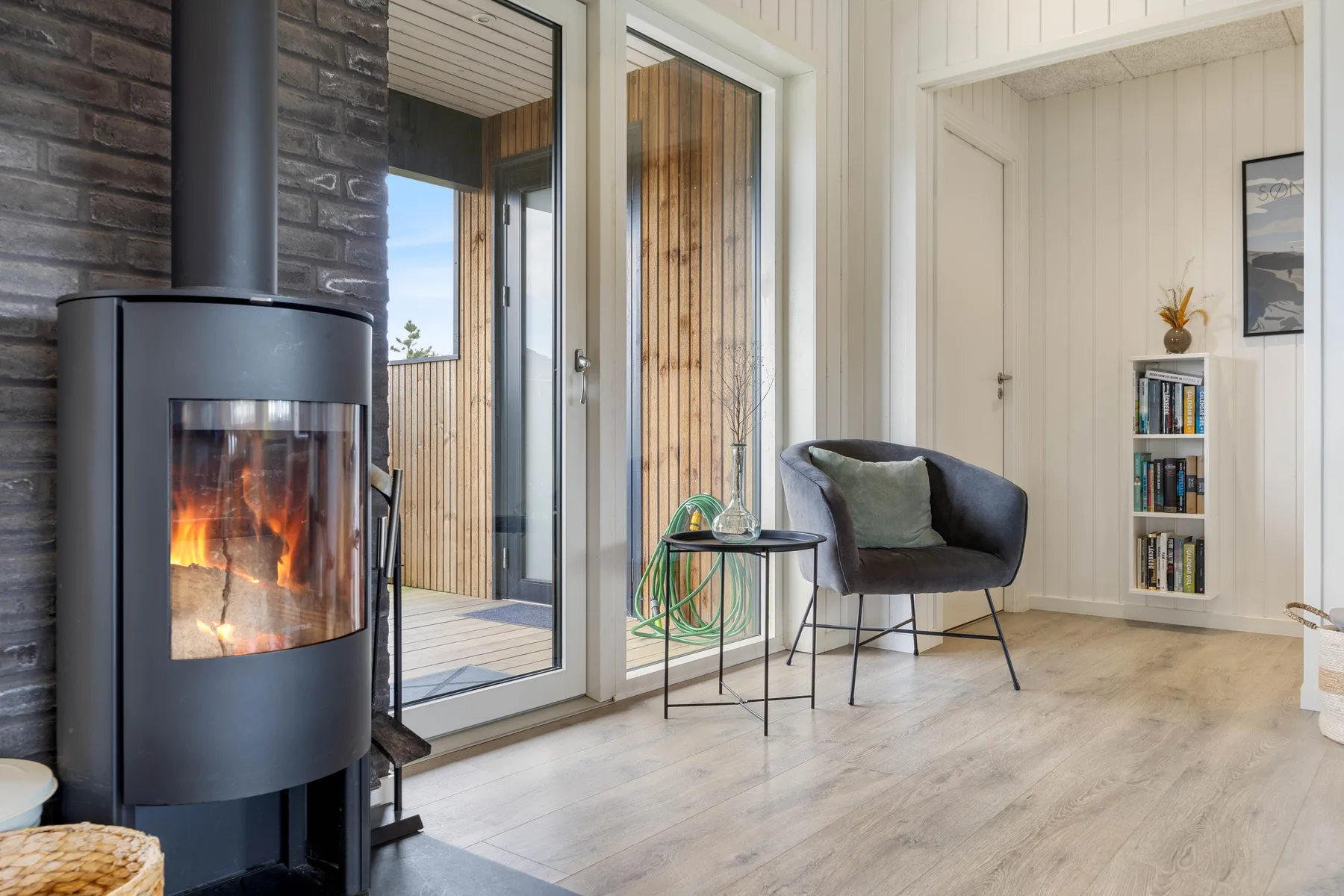 A bright living room with a wood-burning stove and a lounge chair.
