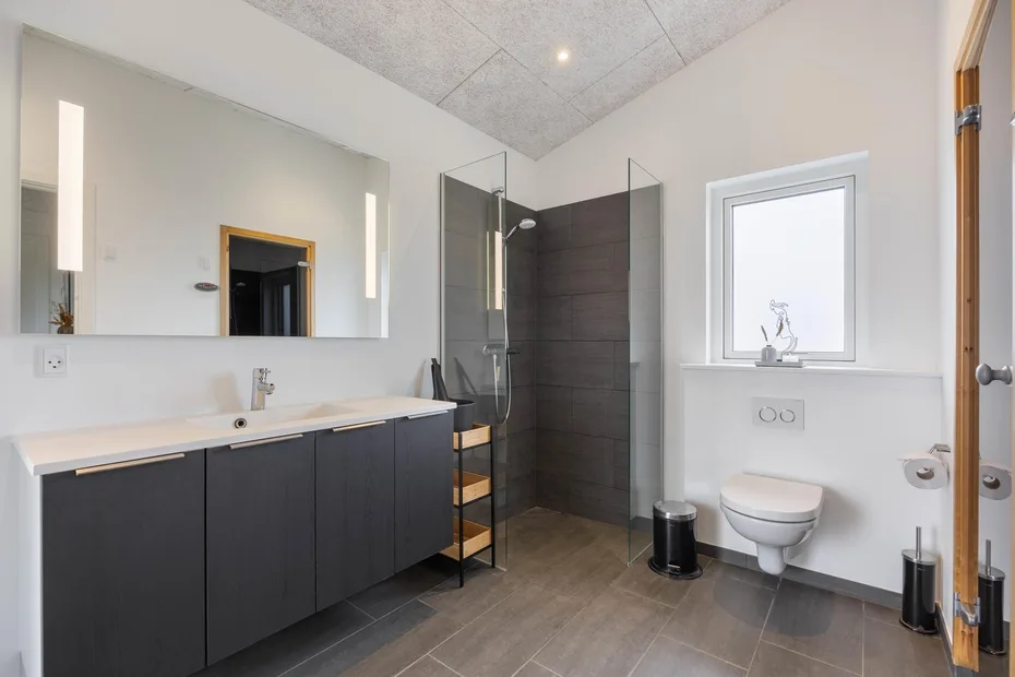 A modern bathroom with a long vanity, mirror, and walk-in shower.