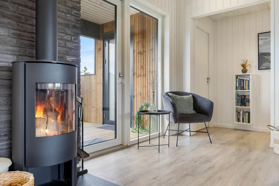 A bright living room with a wood-burning stove, glass doors, and seating.