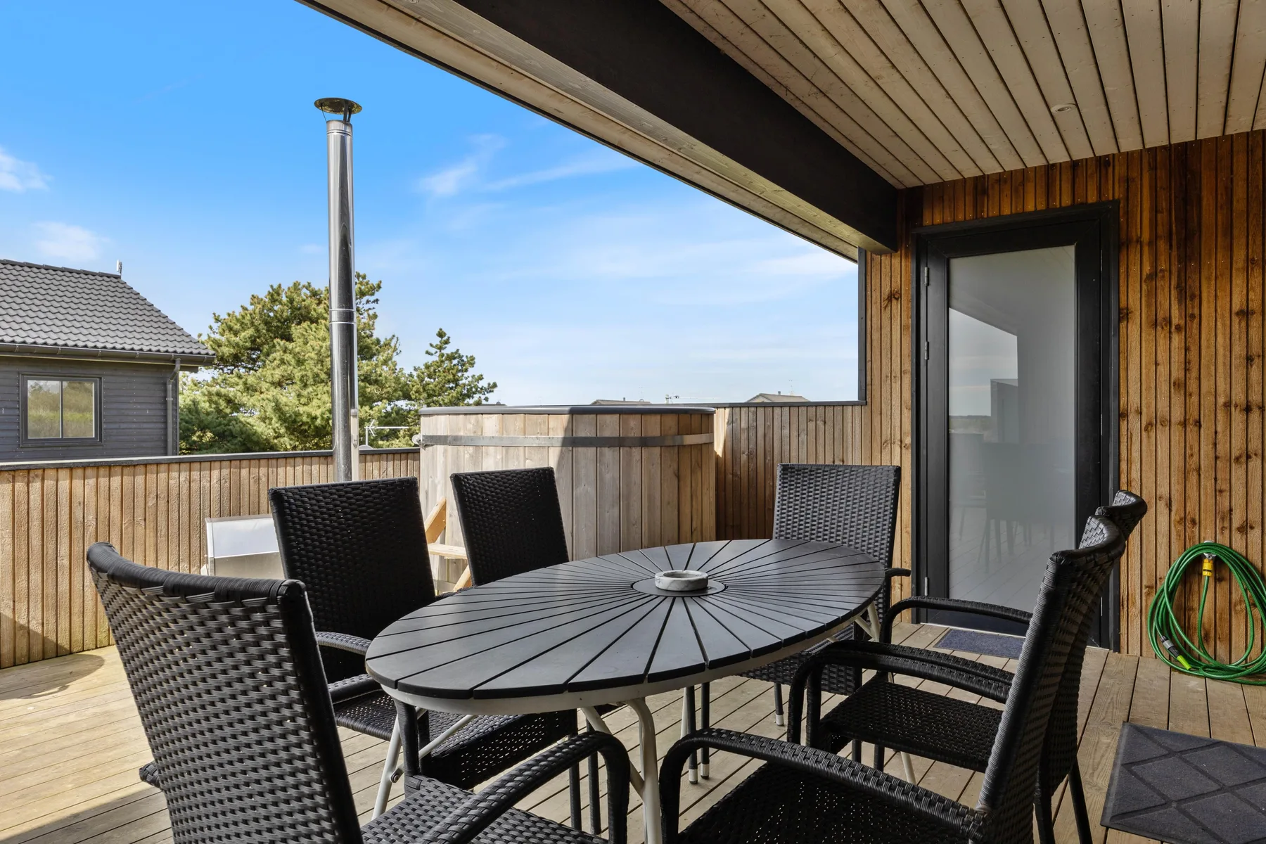 A covered wooden deck with outdoor seating and a round table.