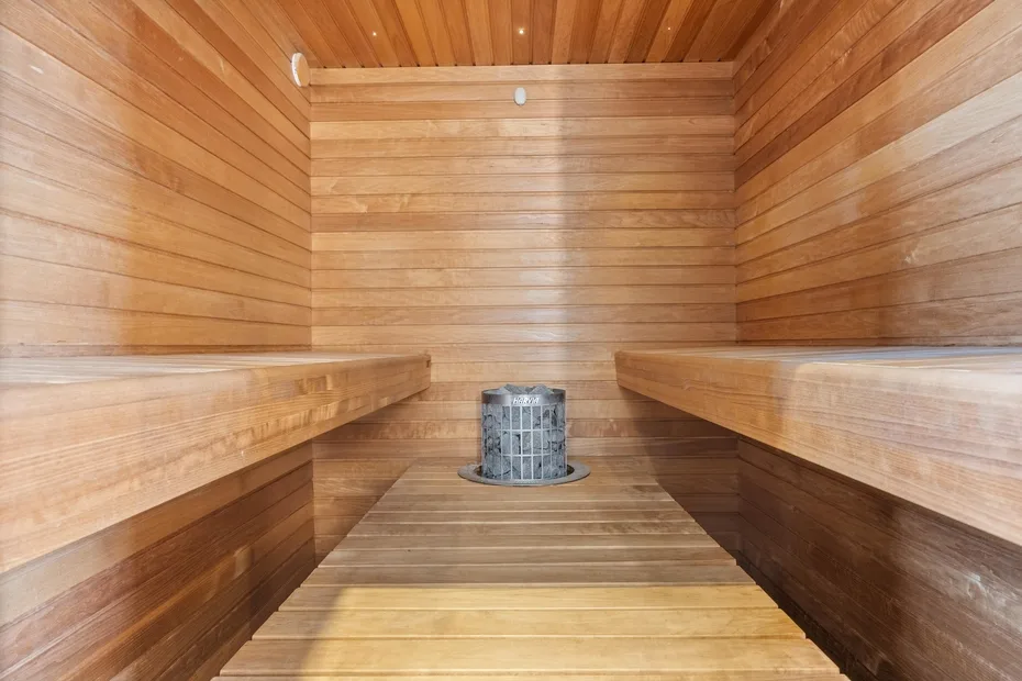 A wooden sauna room with tiered benches and a heater.
