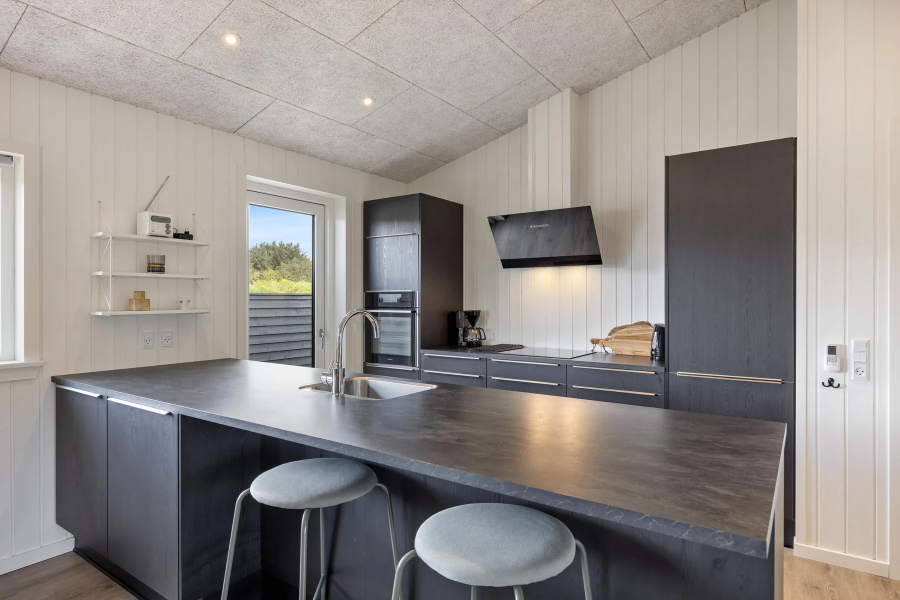A modern kitchen with a dark island and built-in appliances.