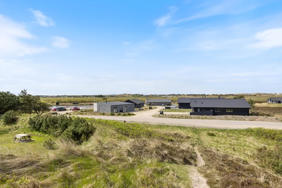 A rural property with low buildings, grassy fields, and a dirt path.