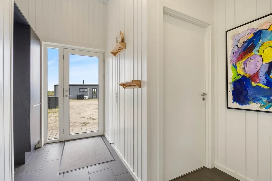 A bright entry hall with a glazed exterior door and colorful wall art.