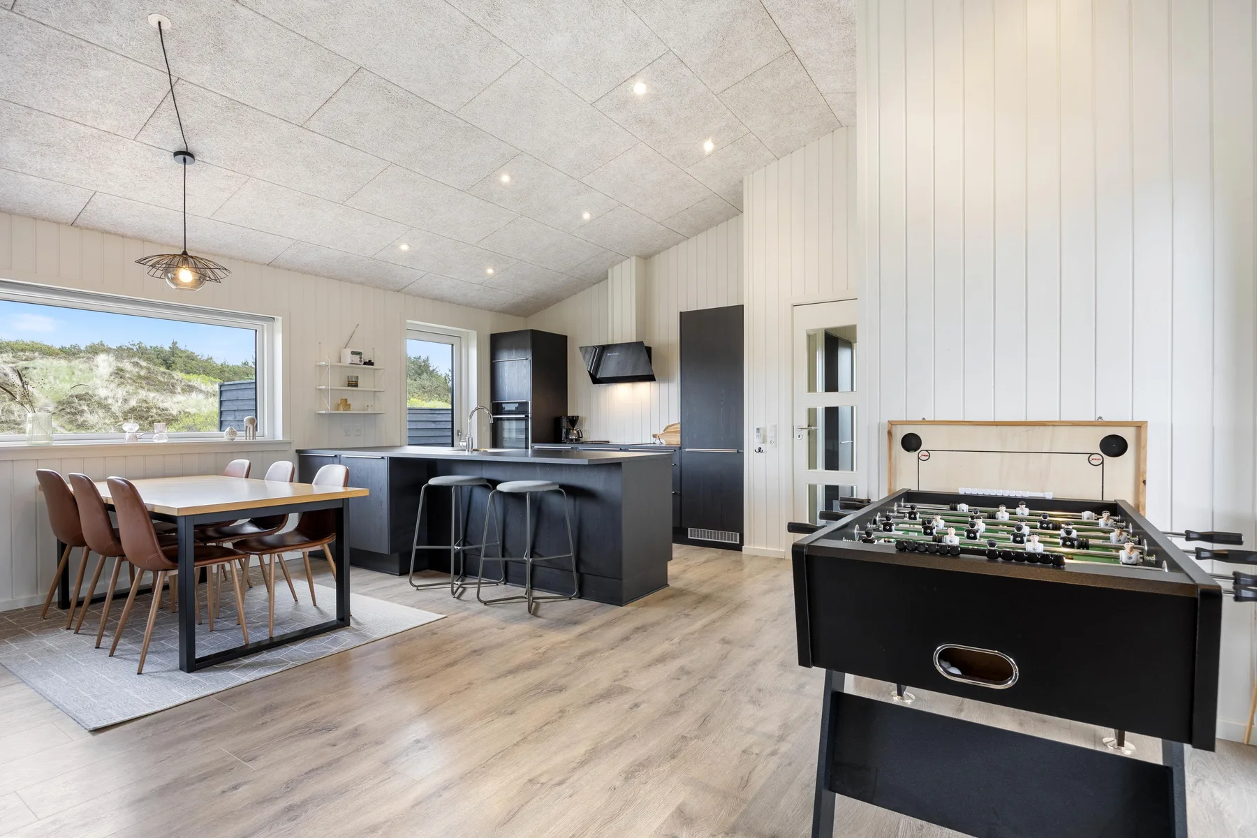 An open-plan kitchen and dining area includes a foosball table.
