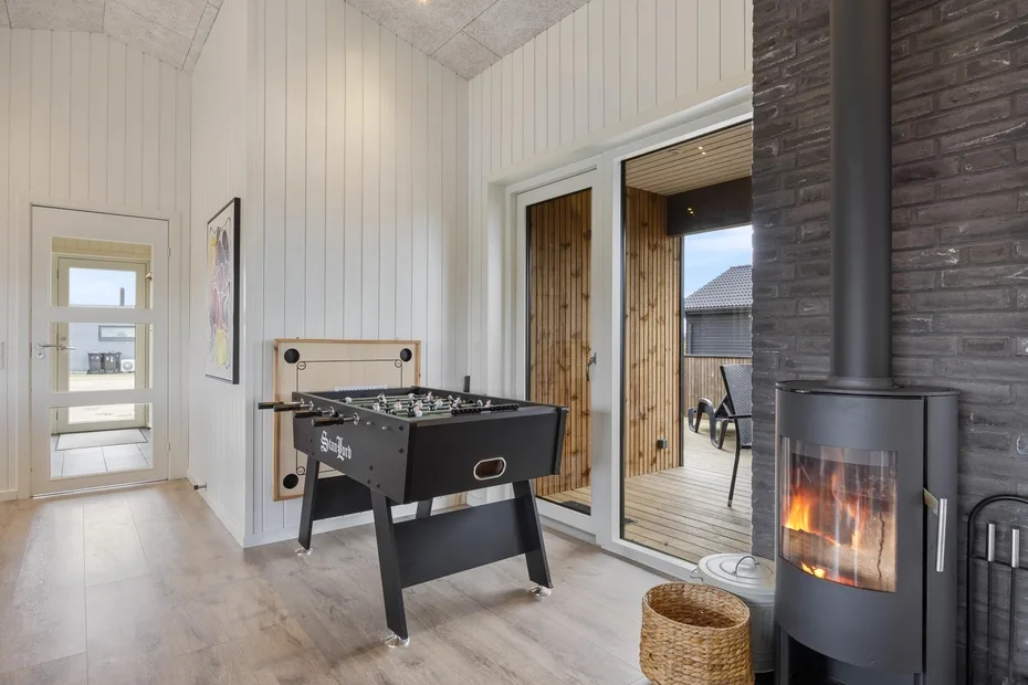 A bright game room with a foosball table and a wood-burning stove.