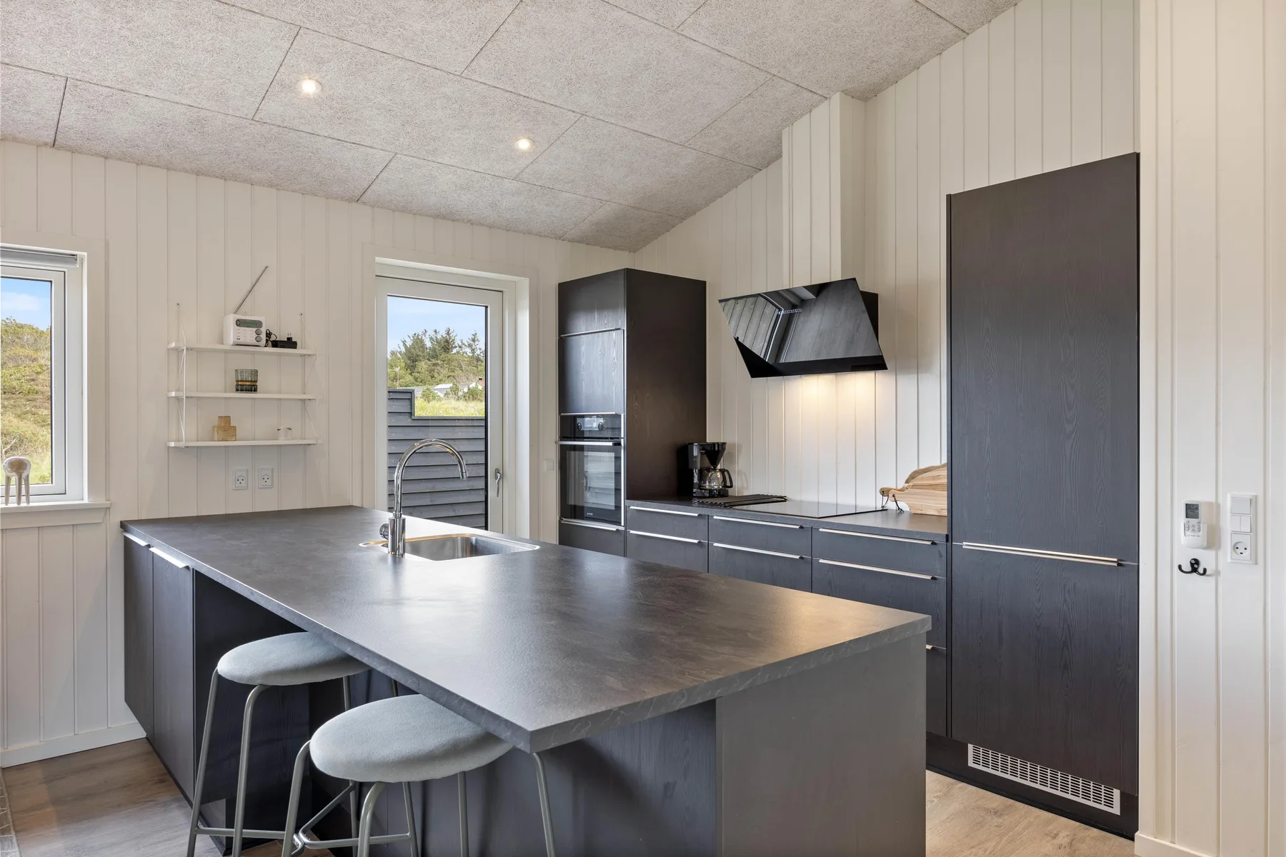 A modern kitchen with a large island and dark cabinetry.
