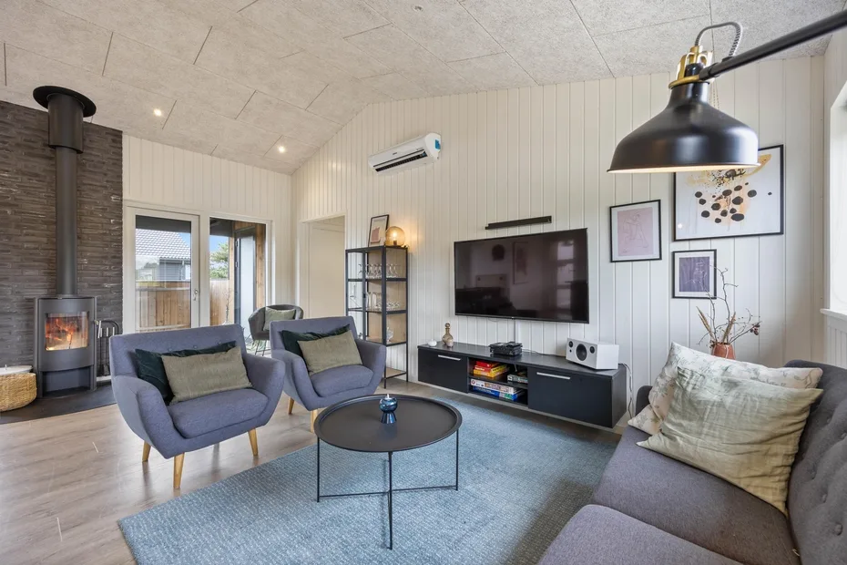 A bright living room with seating, a television, and a wood-burning stove.