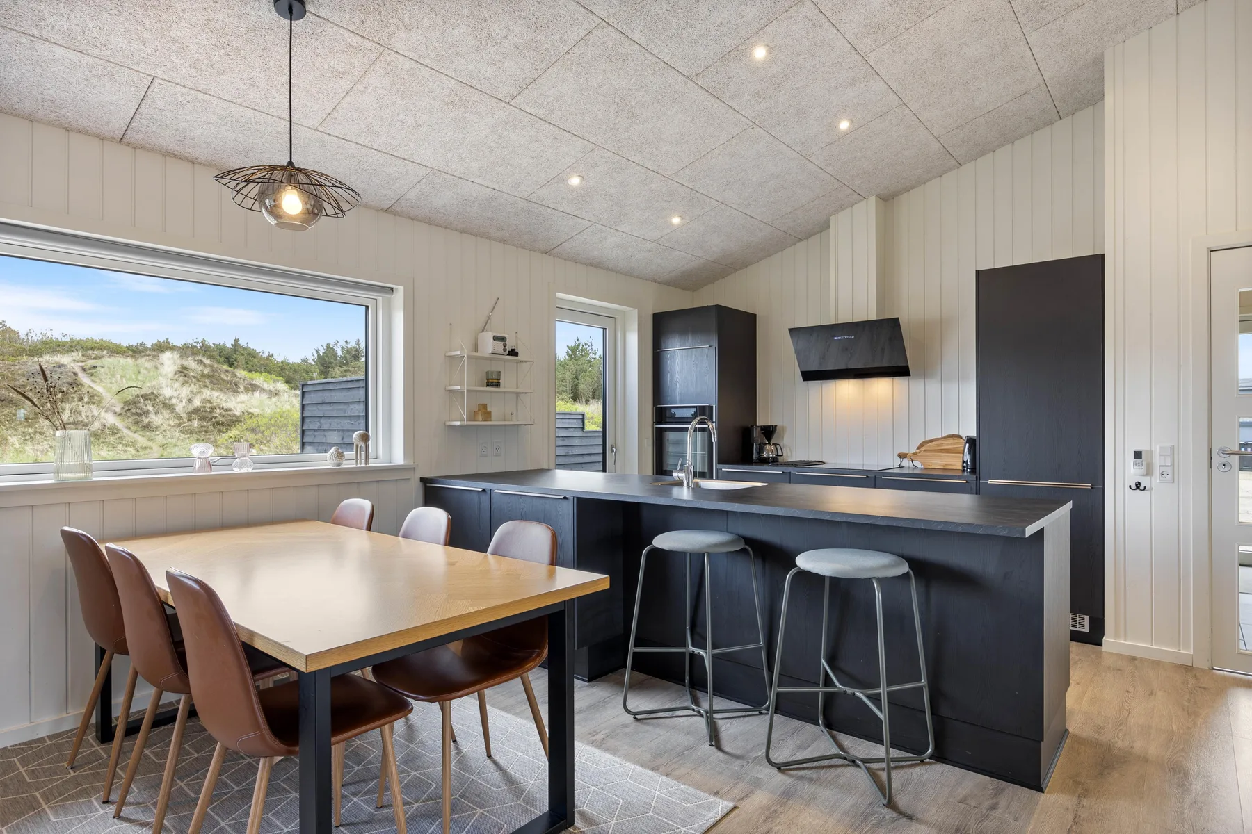 A dining area and kitchen with a table and bar seating.