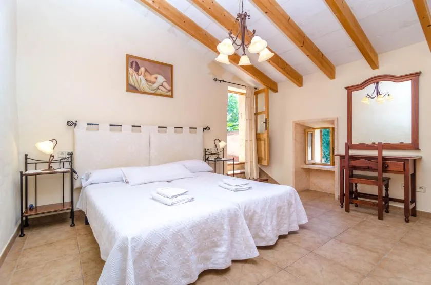 A bedroom with a large bed, bedside tables, and exposed ceiling beams.