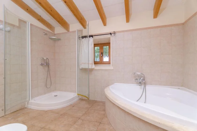 A tiled bathroom with a glass shower and a large bathtub.
