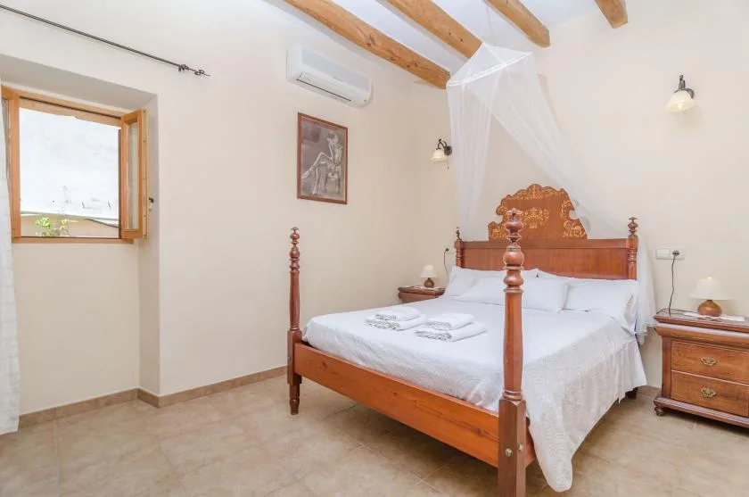 A bedroom with a wooden bed, white linens, and exposed ceiling beams.