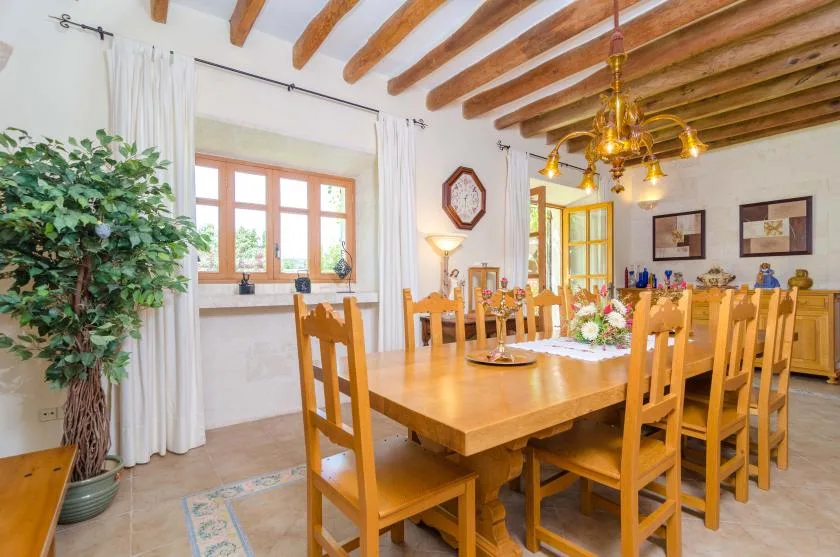 A dining room with a long wooden table set with dishes and flowers.