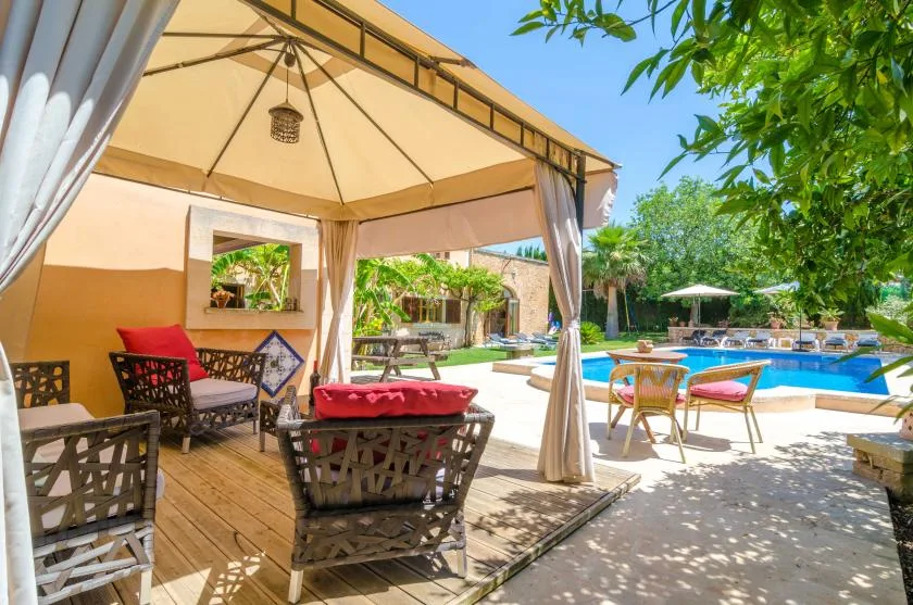 A shaded outdoor seating area opens onto a swimming pool and garden.