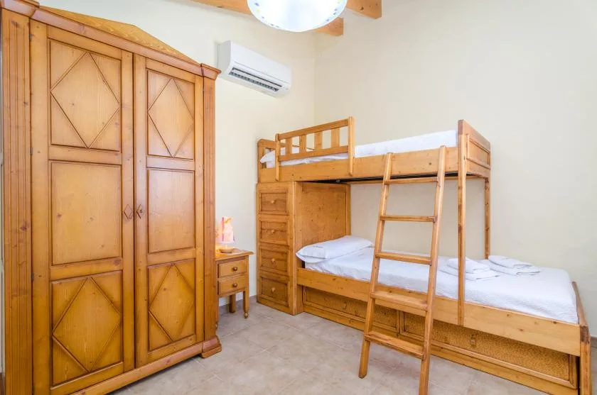 A bedroom with wooden bunk beds and a large wardrobe.