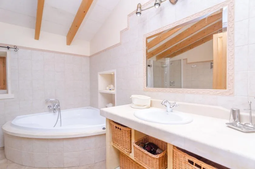 A bright bathroom with a bathtub and a long vanity beneath a large mirror.