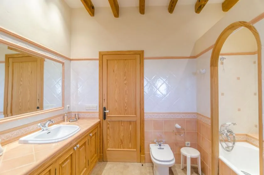 A bathroom with a wooden vanity, sink, and tiled walls.