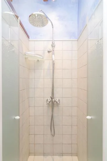 A tiled shower with a rainfall showerhead and handheld sprayer.
