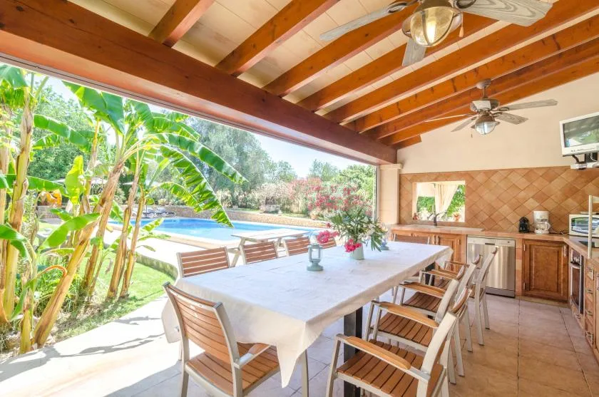 A covered outdoor dining area opens onto a garden and swimming pool.