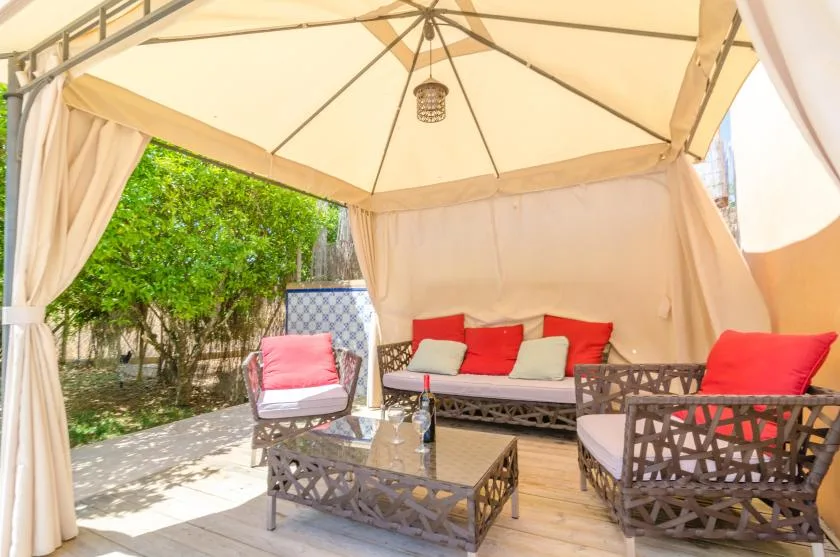 A covered outdoor seating area with cushioned furniture and curtains.