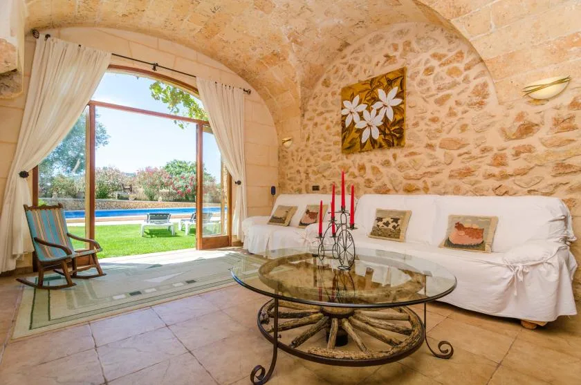 A vaulted living room opens through a curtained doorway onto a garden and pool.