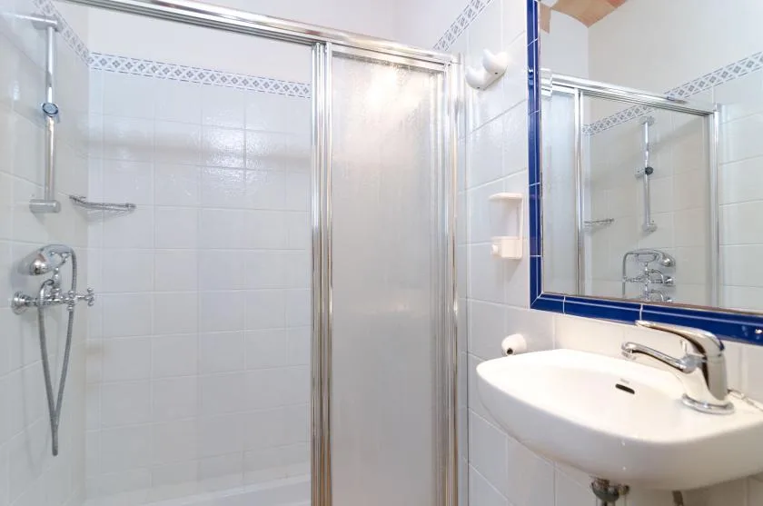 A tiled bathroom with a shower and a wall-mounted sink.