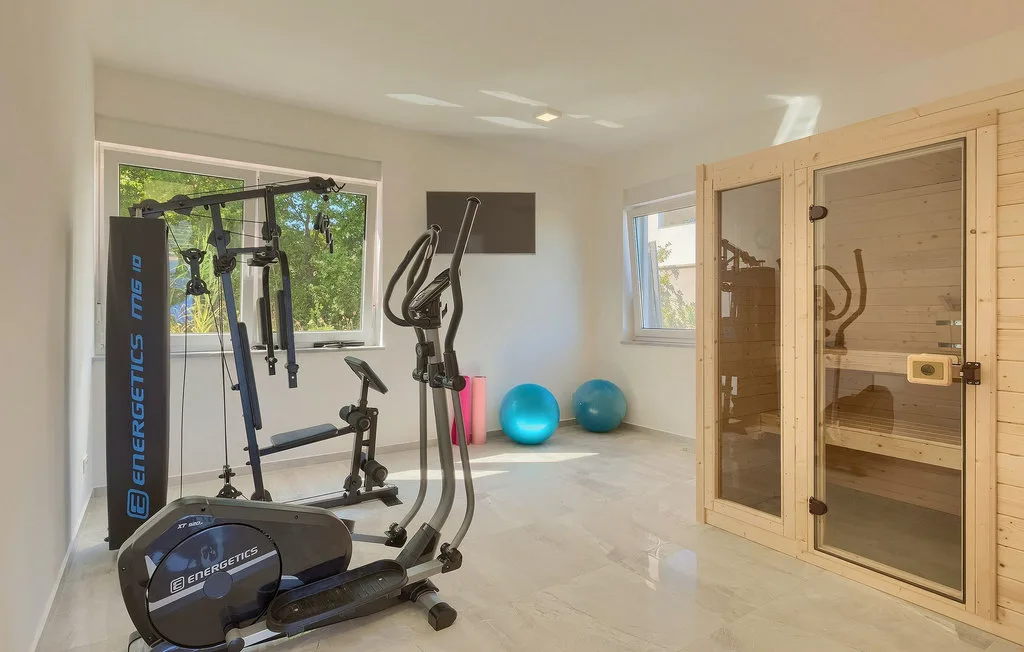 Una sala de ejercicios con equipos de entrenamiento, pelotas y una sauna de madera.