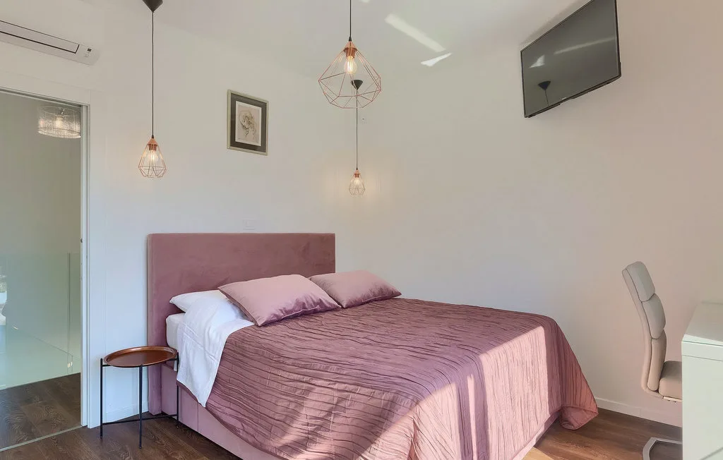 Un dormitorio con una cama doble vestida con ropa de cama rosa.