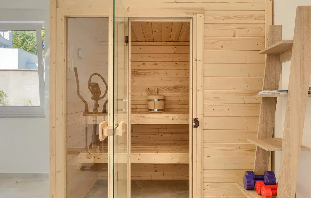 Una sauna de madera con bancos escalonados y una puerta de vidrio.