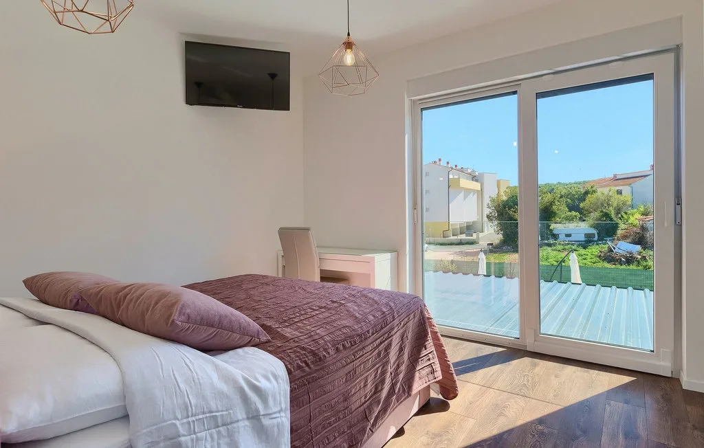 Un dormitorio con una cama junto a grandes puertas de vidrio y vistas al jardín.