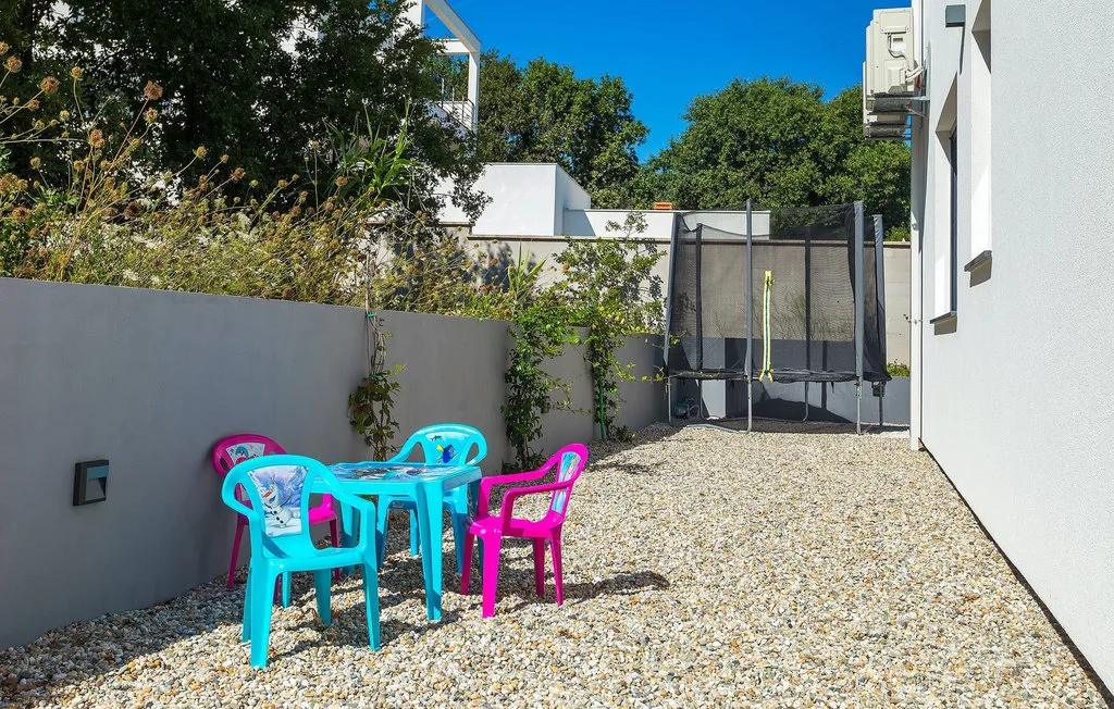 Un patio exterior de grava con asientos de colores y un trampolín.