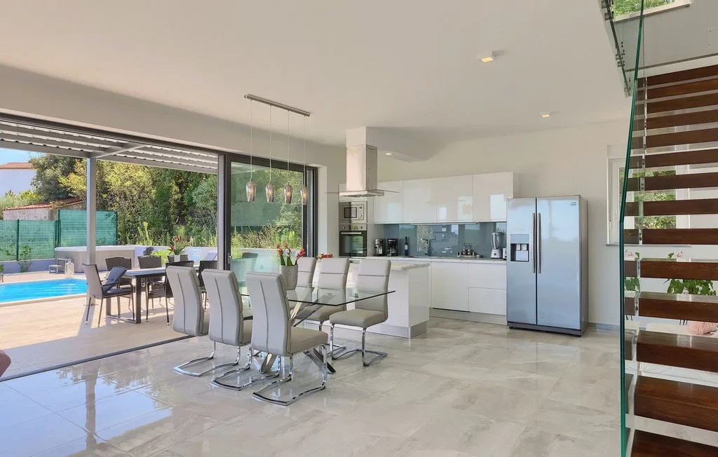 Una luminosa cocina y comedor de concepto abierto dan a un patio y una piscina.
