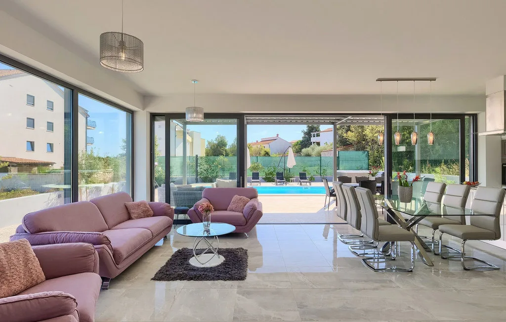 Una luminosa sala de estar y comedor da a un patio y una piscina.