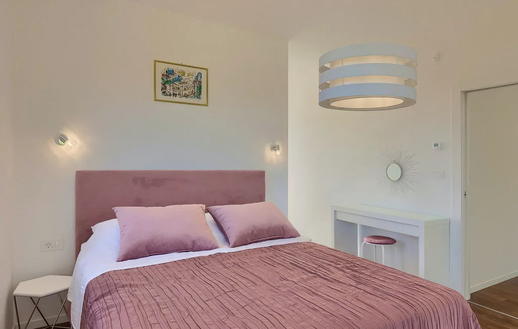 Un dormitorio con una cama cubierta de rosa y un pequeño escritorio al lado.