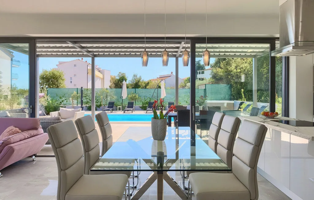 Un comedor se abre a un patio con piscina y asientos al aire libre.