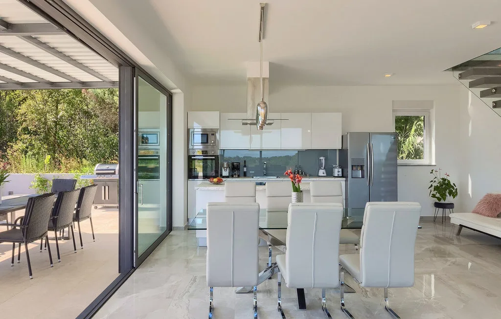 Un luminoso comedor de planta abierta y cocina, con puertas de vidrio que dan a un patio.