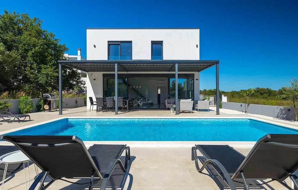 Una casa moderna da a una piscina y un patio pavimentado.