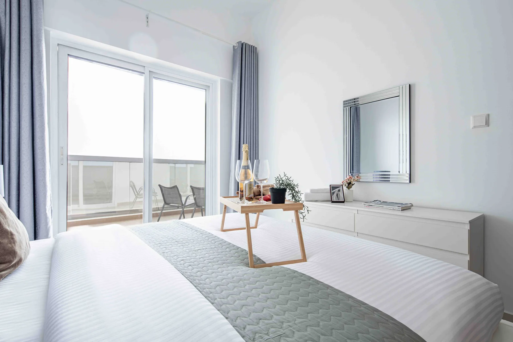 Un dormitorio luminoso con una cama, una mesa baja y grandes puertas de vidrio.