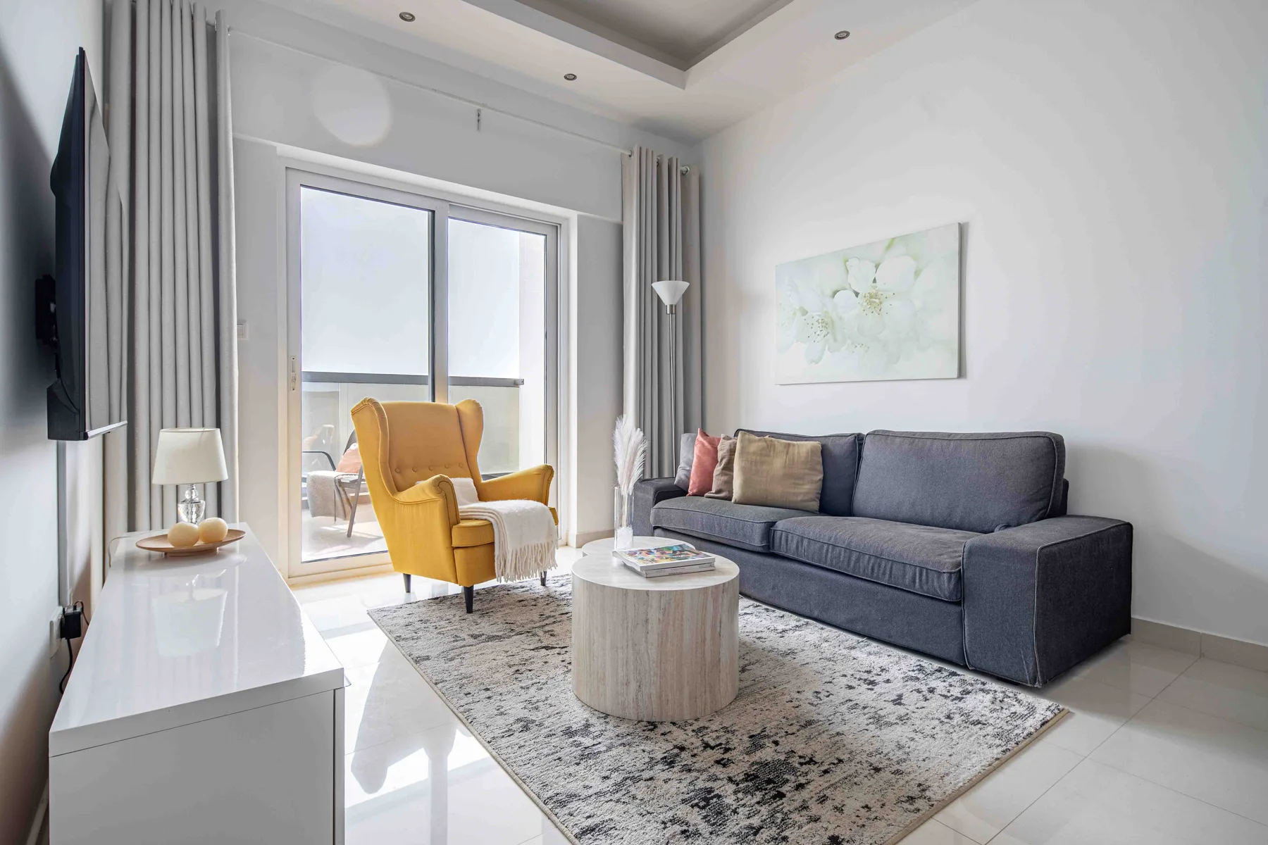 Sala de estar con sofá y sillón junto a una puerta de cristal.
