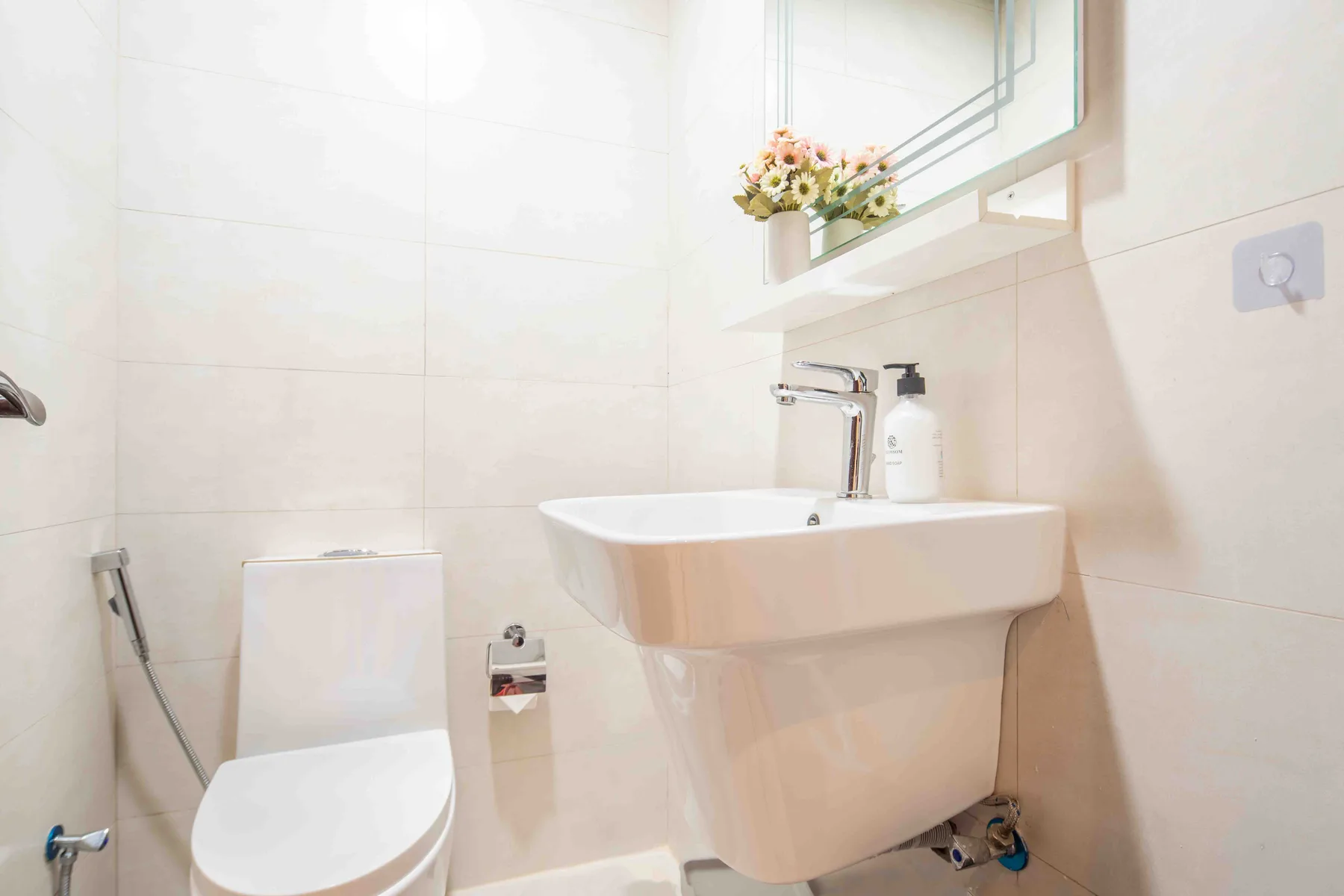 Un baño luminoso con inodoro, lavabo y espejo.
