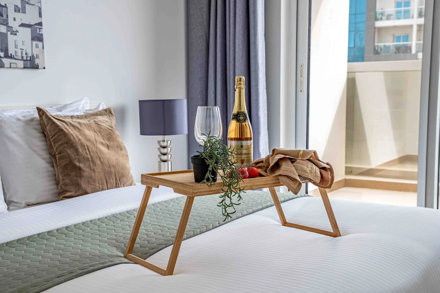 Un dormitorio con una mesa baja sobre la cama junto a una ventana luminosa.