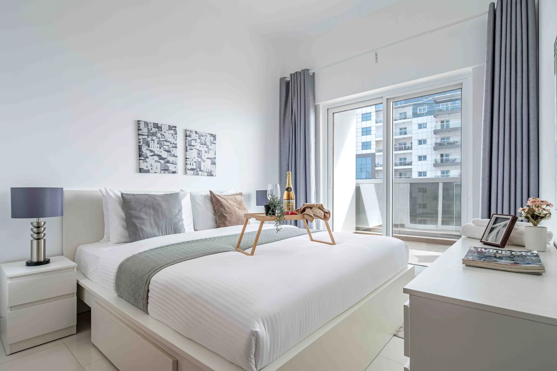 Un dormitorio luminoso con una cama bien hecha junto a una ventana grande.