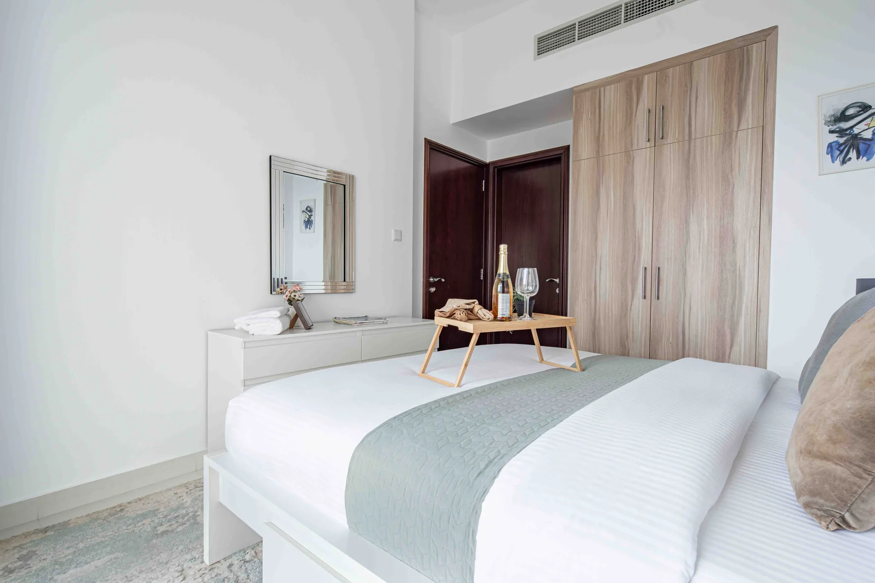 Un dormitorio luminoso tiene una cama bien arreglada y un armario grande de madera.