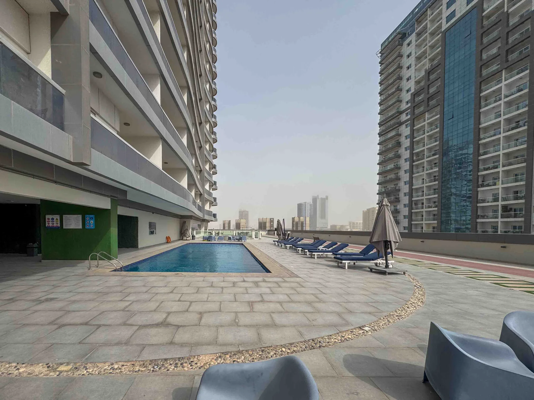 Una piscina al aire libre está en una terraza pavimentada entre edificios altos.