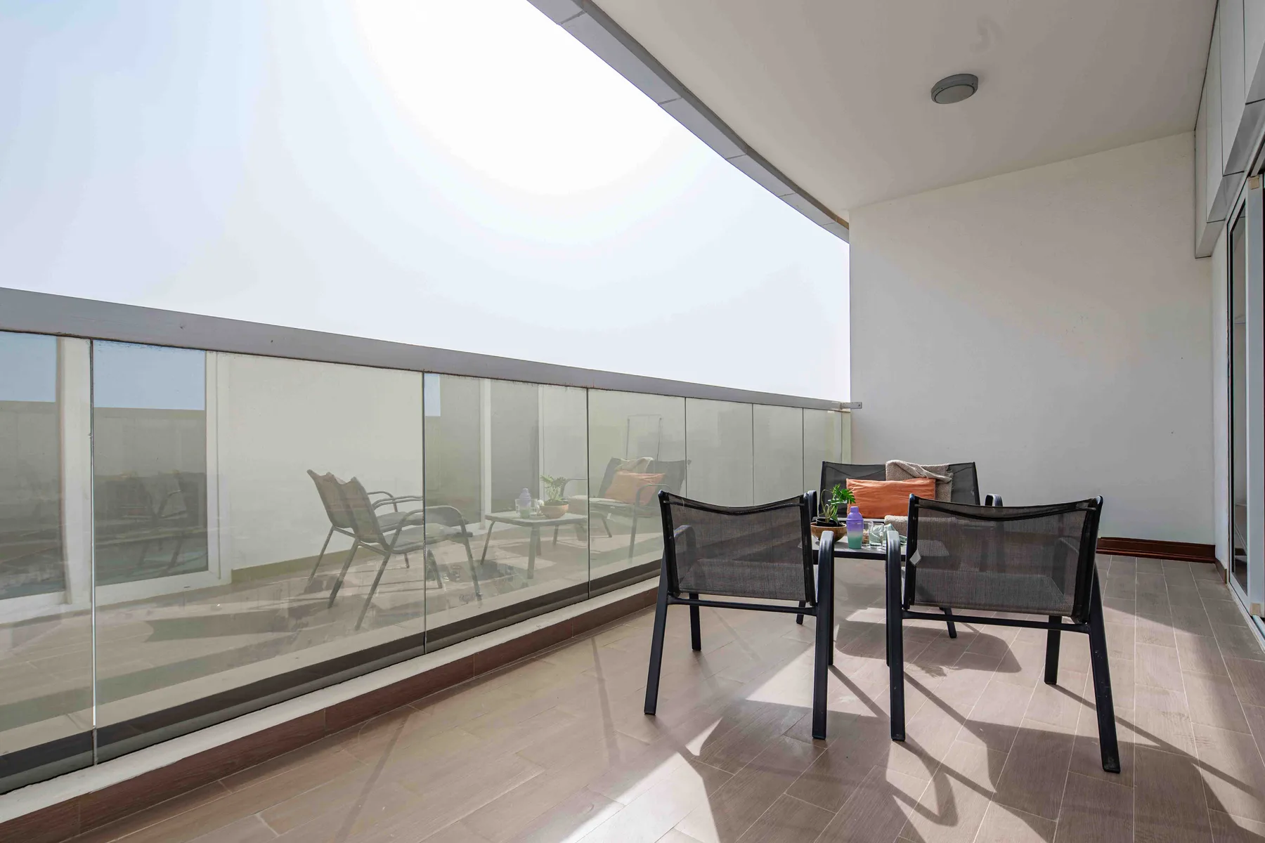 Una terraza cubierta con asientos al aire libre y una barandilla de vidrio.