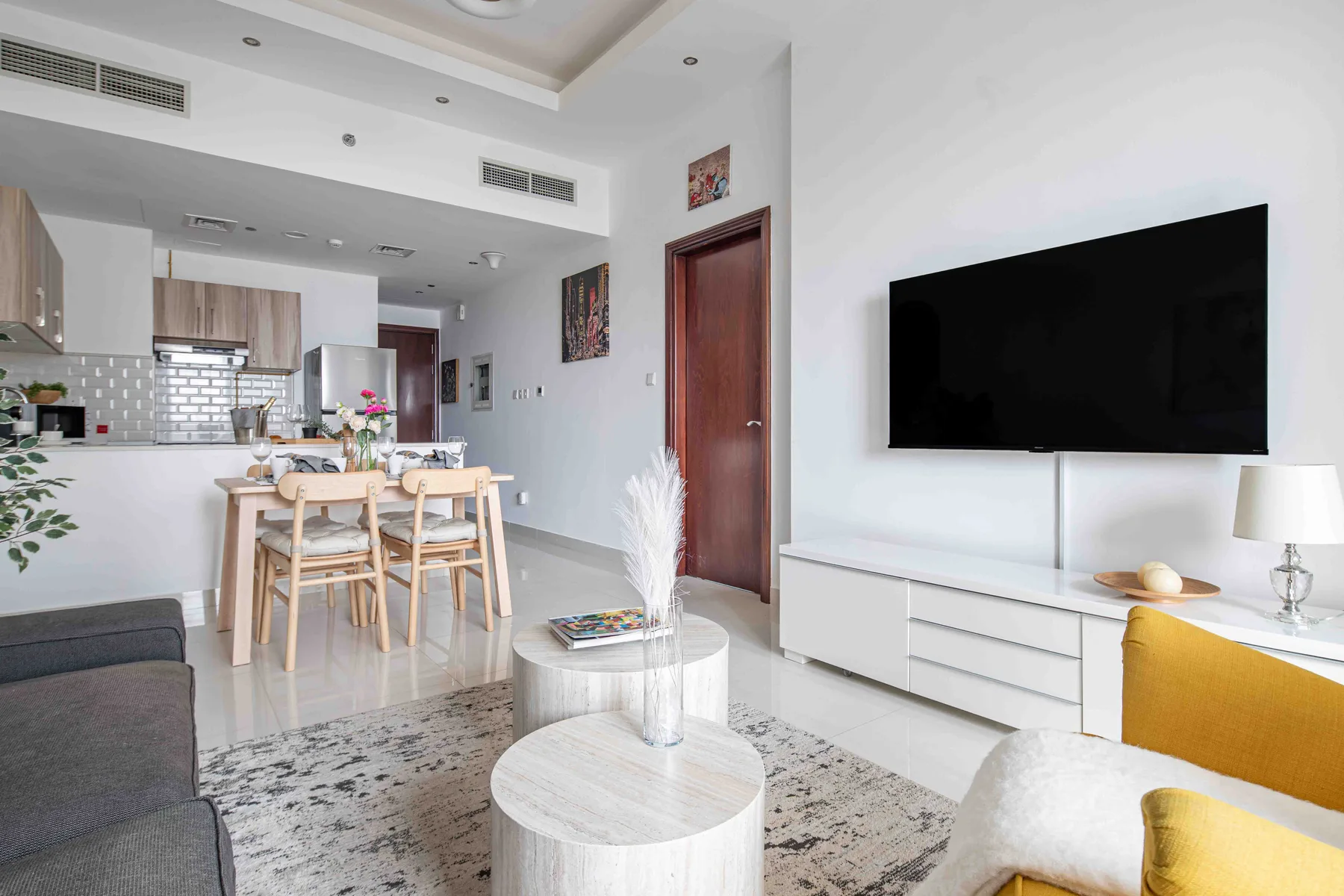 Una sala luminosa con televisor, asientos y un comedor.