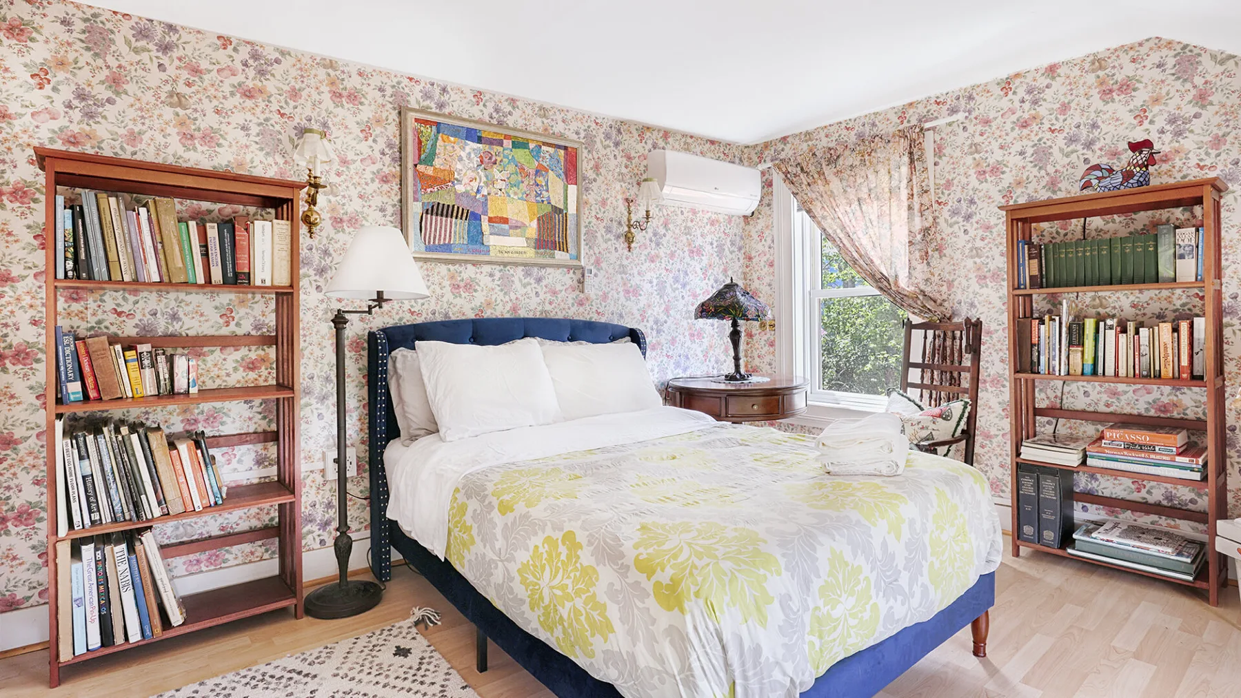 A bedroom with a bed covered in a white quilt with yellow floral patterns.