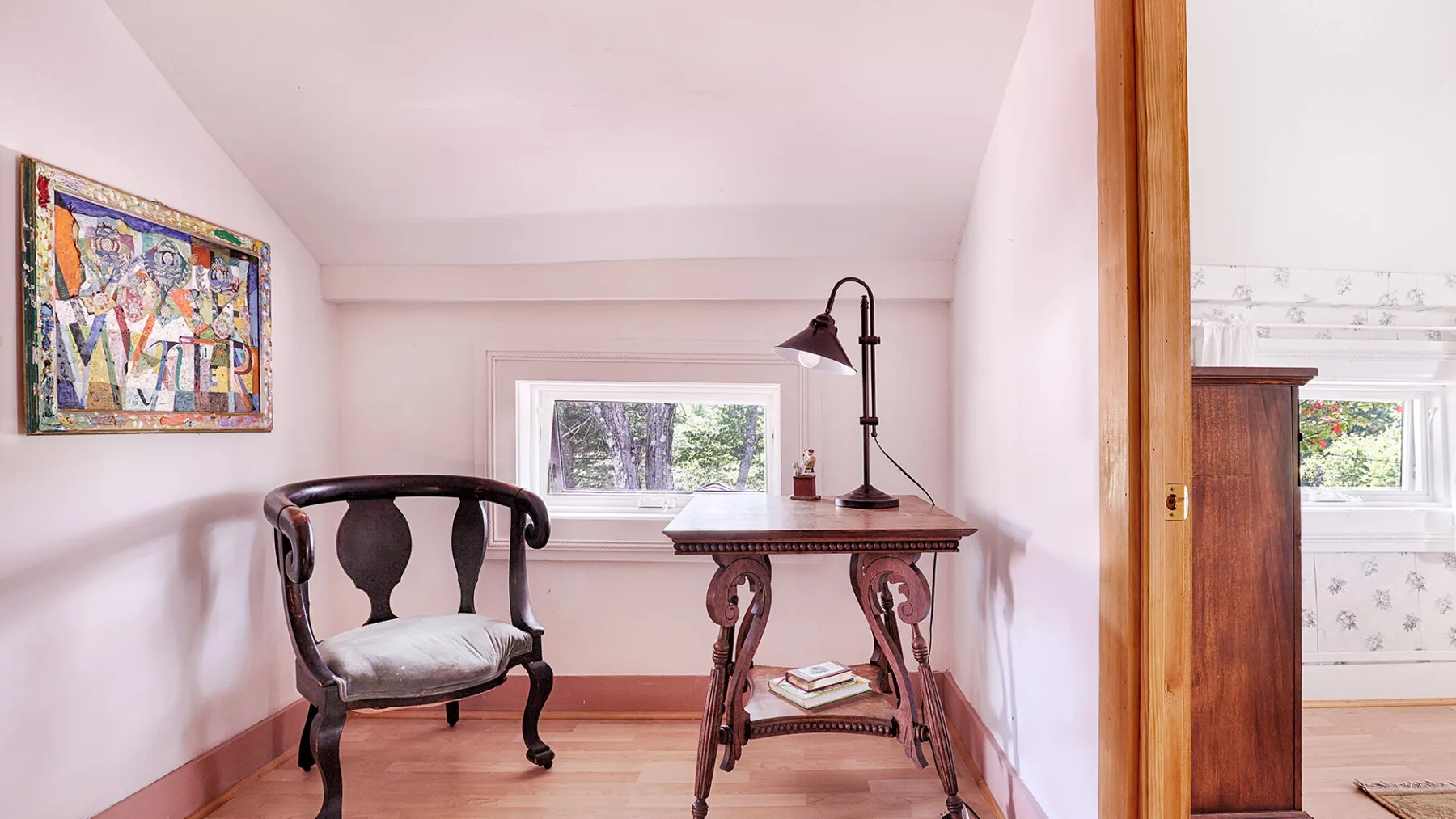 A small sitting area with a wooden chair, writing desk, and window.