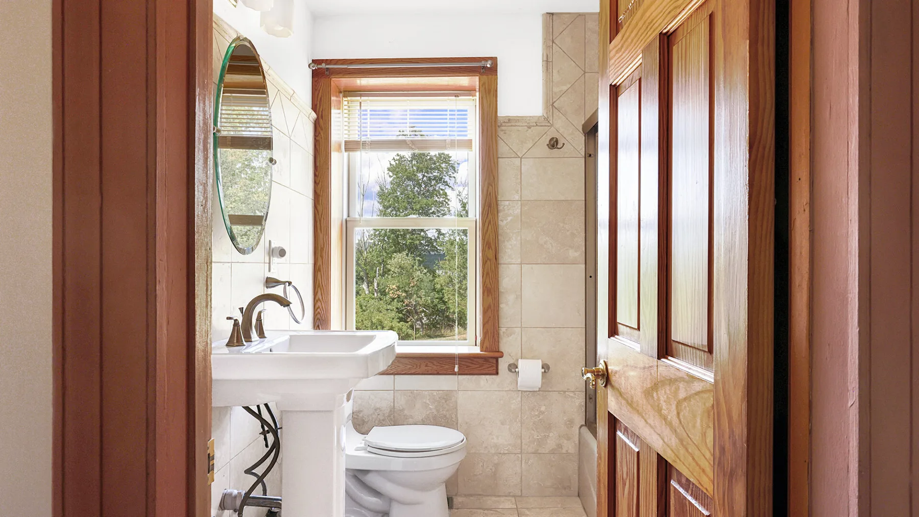 A bathroom with a sink and toilet beside a window.