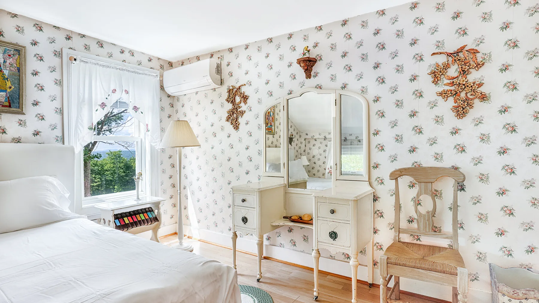 A bedroom with a bed, window, and dressing table.